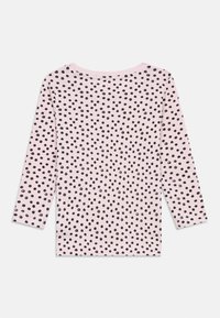 Ružová košeľa s dlhým rukávom, čiernymi bodkami, okrúhlym výstrihom, mäkkou tkaninou a žebrovanými manžetami. Vzor je rovnomerne rozložený po celej látke.