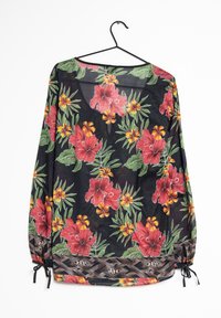 Blusa floreale con maniche lunghe, realizzata in un tessuto nero decorato con fiori rossi e gialli; include polsini elastici e orlo con motivo.