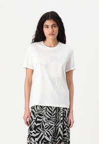 Vit bomull t-shirt med tre blanka, prydliga rosettmönster i olika storlekar. Tyget har en slät yta; korta ärmar är uppvikta.