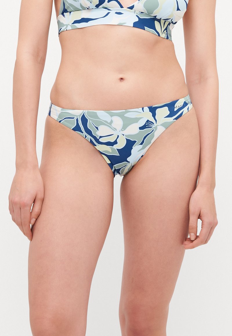 Ziedu bikini komplekts ar tumši zilu pamatni un gaismas zaļiem un krēmkrāsas ziedu rakstiem. Topam ir v-veida dekoltē dizains; apakšdaļai ir zemas vidukļa līnijas.