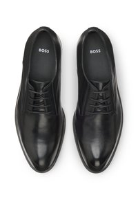 Schwarze Leder-Halbschuhe mit glatter Oberfläche, spitzer Zehenform und sechslöchrigem Schnürdesign. "BOSS"-Logo sichtbar auf der Innensohle.