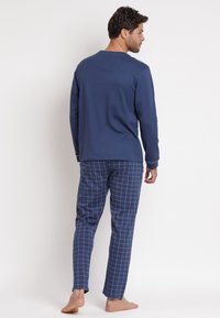 Top a maniche lunghe navy con scollatura rotonda abbinato a pantaloni a quadri navy e bianchi. Tessuto morbido con una vestibilità comoda.