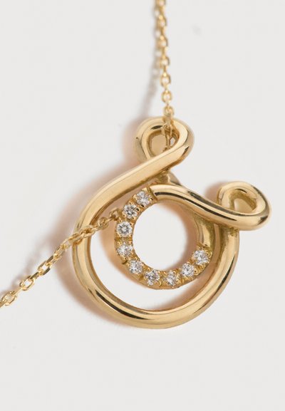 Gold pendant necklace with an abstract loop design encircling a smaller circle of clear sparkling gemstones.