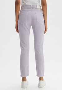 Jean lavande clair avec une coupe à jambe droite, cinq poches, et des détails de couture subtils, associé à des baskets blanches.