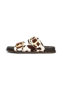 Bruine en witte cow-print slippers met twee verstelbare gouden gespen, een bruin textuur voetbed en een donkerbruine rubberen zool.