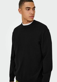 Black sweater with a round neckline, ribbed cuffs, and hem. Made of soft fabric, featuring a relaxed fit without visible patterns.