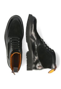 Botas de tobillo de cuero negro y ante con forro naranja, punta redonda, parte delantera con cordones y suela de goma texturizada, con una lengüeta en el talón.