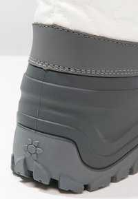 Bota impermeable gris con suela de goma texturizada, parte superior de tela blanca acolchada y costuras en contraste. Presenta un diseño floral en el talón.