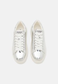 Weiße Sneakers mit silbernem, verspiegeltem Zehenbereich, Schnürung vorne und Logodetail auf der Zunge. Glatte Textur mit einem klobigen Sohlen-Design.