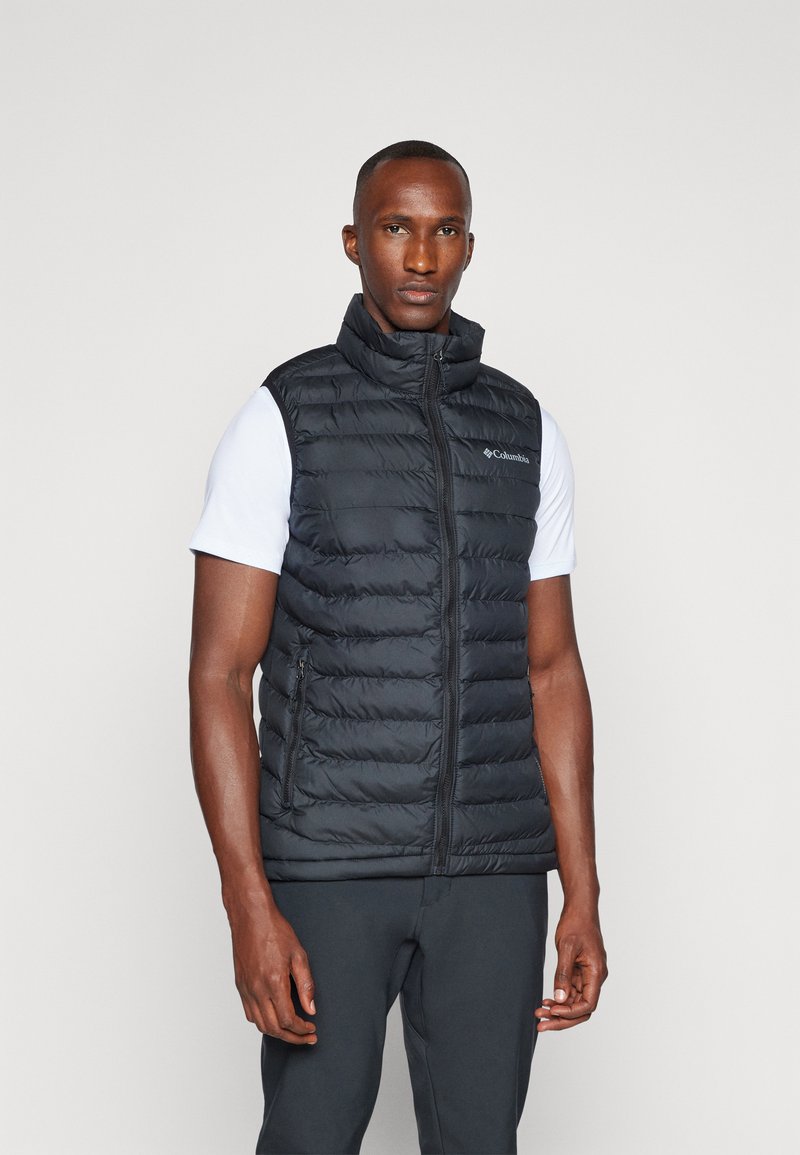 Sort puffervest med høj krave, lynlås foran og sidelommer, med kviltet design og placeret logo. Båret over en hvid skjorte.