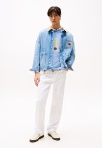 Denim jacket with a light blue wash, tan collar, front pockets; paired with a light blue t-shirt and white straight-leg pants, off-white sneakers.