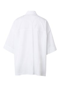 Vue de dos d'une chemise blanche unie à manches courtes, coupe large et col classique, présentée sur un fond blanc.
