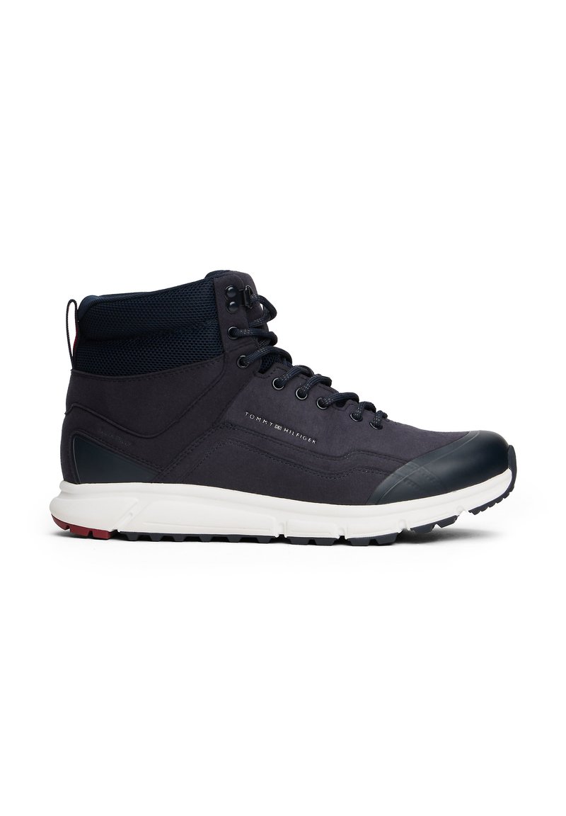 Mid-top hiking boots in dark navy fabric with mesh accents, a rubber toe cap, and a white sole featuring a textured grip pattern.