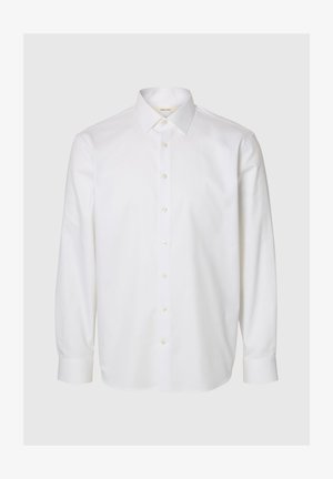Chemise blanche à manches longues en coton, dotée d'un col classique, d'une patte de boutonnage à l'avant et de poignets boutonnés. Texture lisse sans motifs visibles.