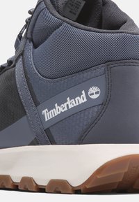Sneaker Timberland blu scuro con tomaia in mesh e sintetico, dettagli testurizzati, logo in rilievo e suola intermedia bianca con suola in gomma.