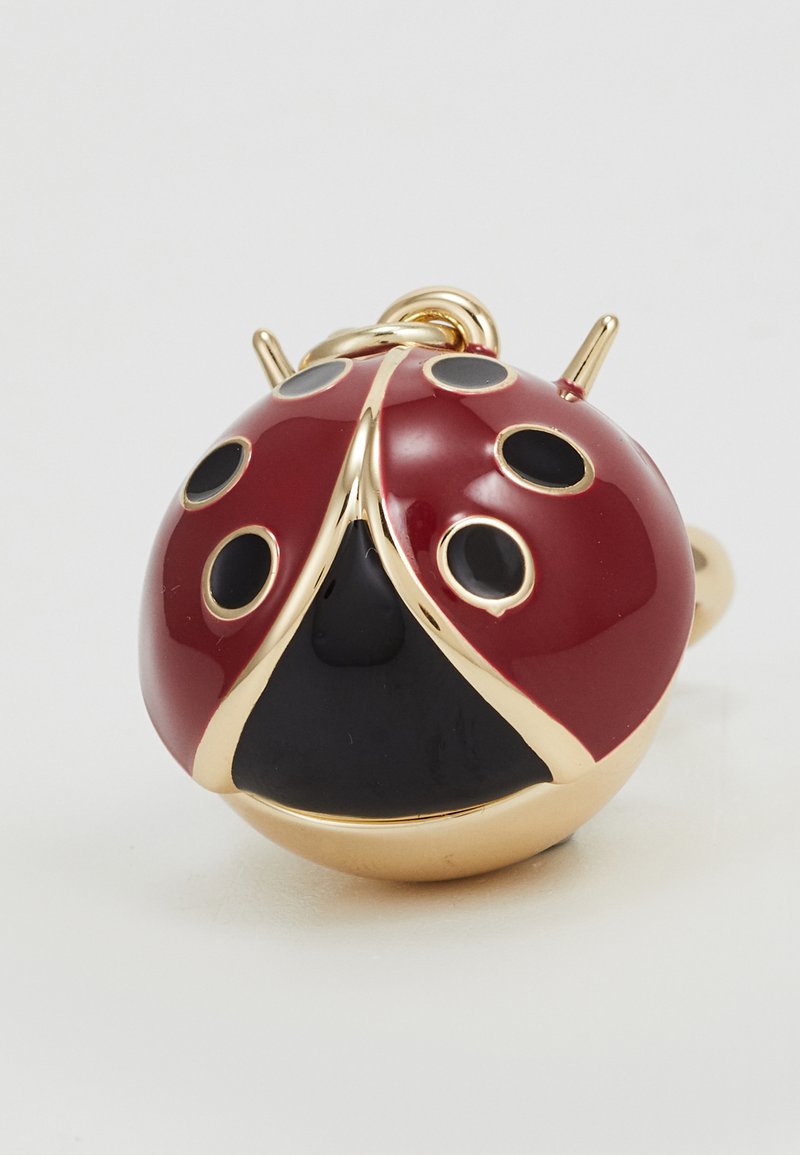 Accessorio a forma di coccinella rosso e nero con finitura in smalto lucido, dettagli dorati e macchie nere. Presenta un anello per il fissaggio.