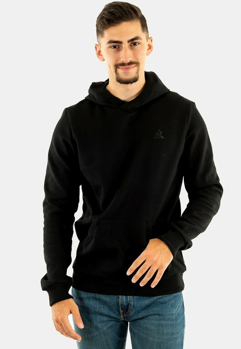 Sudadera negra hecha de una tela suave con capucha ajustable, bolsillo delantero y puños de canalé. Presenta un logo sutil en el pecho.