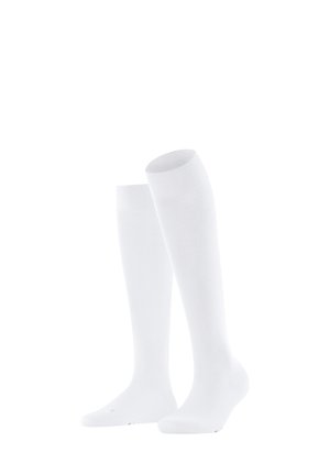Een paar eenvoudige witte kousen tot de knie staan rechtop op een witte achtergrond, en tonen de textuur en geribbelde bovenkanten.