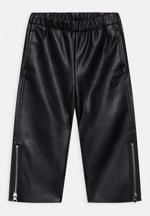 Czarne spodnie z ekologicznej skóry z elastycznym paskiem w talii, bocznymi kieszeniami na zamek i okrągłym logo po lewej stronie.