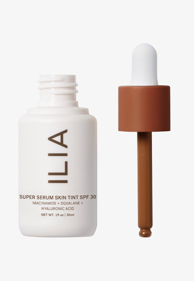 ILIA Super Serum Skin Tint SPF 30 in einer weißen Flasche mit brauner Beschriftung. Enthält einen Tropfer mit einem braunen Deckel und einer konischen Spitze. 30 ml.