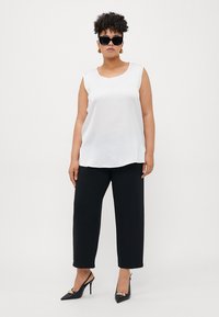 White sleeveless top with a round neckline paired with black wide-leg pants and black pointed-toe heels; accessorized with oversized sunglasses.