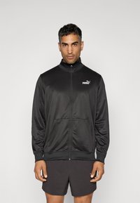 Sort zip-jakke lavet af glat, let materiale med høj krave, der har en frontlomme og et lille hvidt Puma-logo.
