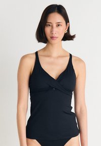 Svart tankini-topp med justerbare stropper, v-hals og en vridd design foran. Laget av elastisk, glatt stoff.