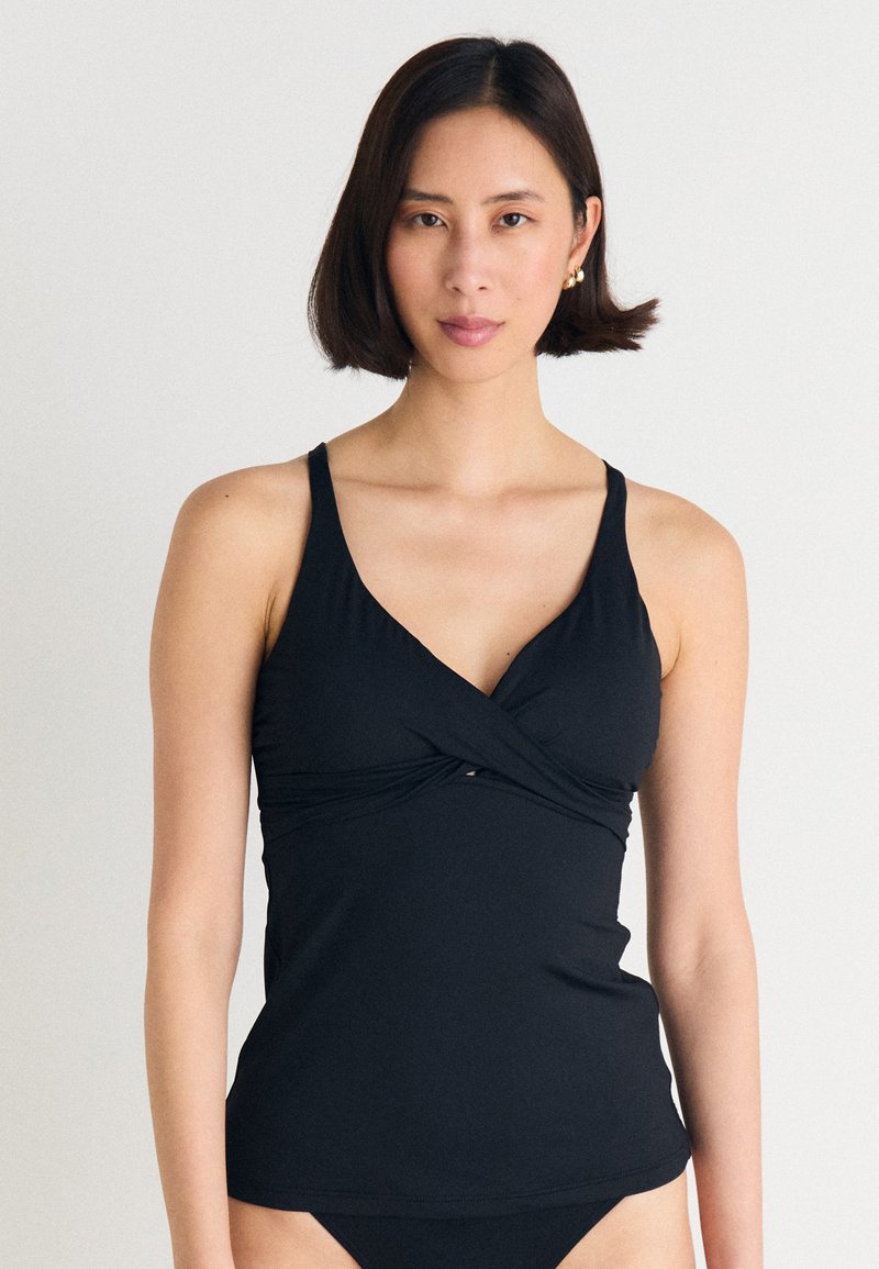 Svart tankini-topp med justerbare stropper, v-hals og en vridd design foran. Laget av elastisk, glatt stoff.