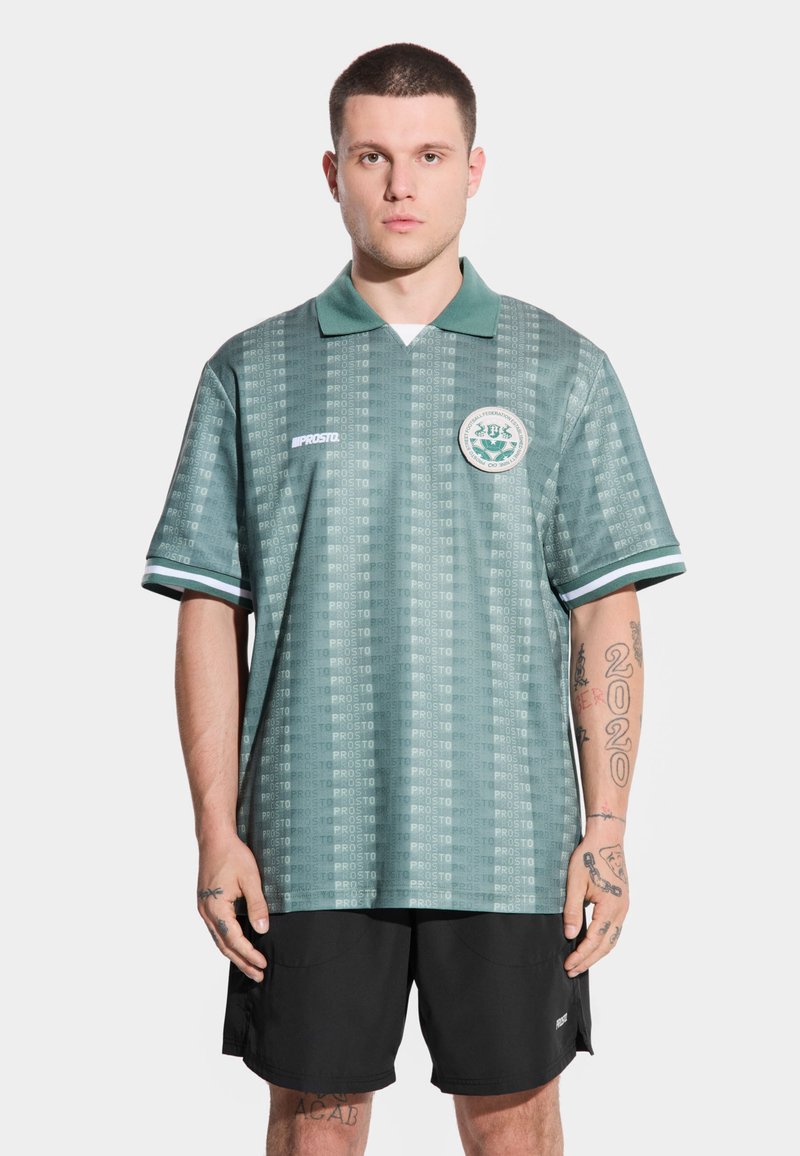 Zielona polo z krótkim rękawem w wzory, z kołnierzykiem, marką "PROSTO" oraz okrągłym logo na lewej piersi.