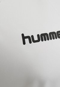 Hvidt stof med en glat tekstur, der har ordet "hummer" i fed, små bogstaver i sort. Ingen yderligere mønstre eller accenter synlige.