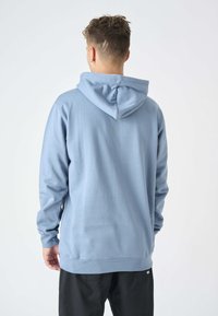 Felpa blu chiaro con cappuccio regolabile, maniche lunghe e vestibilità morbida. Presenta una texture soffice e polsini e orlo a coste.