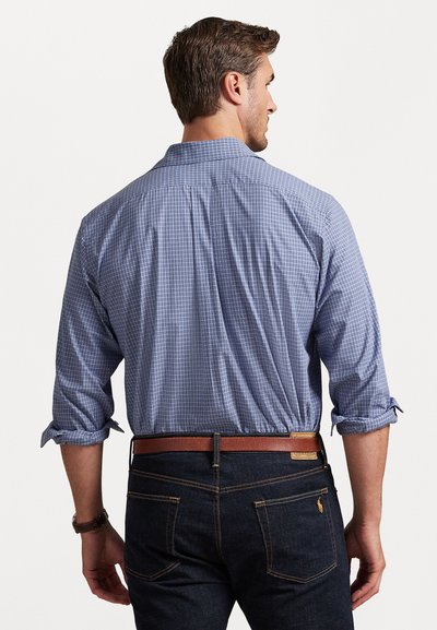 Cămașă bărbătească cu nasturi, cu un model în carouri albastre și albe. Prezintă mâneci lungi, o guler și este asortată cu blugi negri și o curea maro.