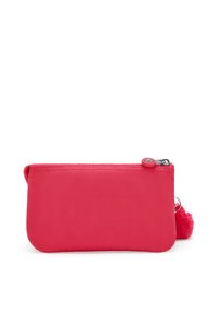 Roze nylon tas met een gladde textuur, ronde randen en een ritssluiting. Heeft een pluizige pomponaccent aan de zijkant.