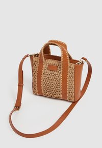 Woven straw and faux leather handbag in tan with a textured design, dual handles, and an adjustable strap. Note stitching details.