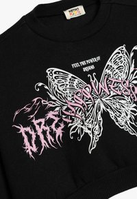 Sudadera negra con cuello y dobladillo acanalados. Presenta un gran gráfico de mariposa en blanco y rosa, con texto estilizado en rosa y blanco.