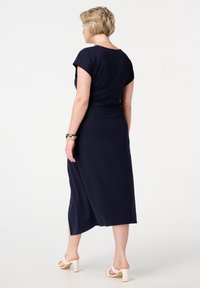 Marineblauwe midi-jurk met korte mouwen, een getailleerde pasvorm en een uitlopende rok. Draag het met beige block-heeled sandalen en een gouden armband.