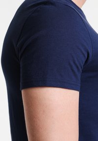 Navy blue cotton t-shirt featuring a round neck and short sleeves, displaying a smooth texture and fitted silhouette.