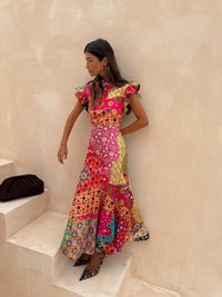 Kleurvolle, bedrukte maxi-jurk met uitlopers; bevat een mix van bloem- en geometrische patronen in rood, roze, geel en groen.