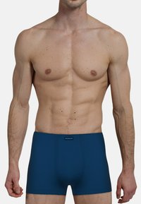Dunkelblaue Herren-Boxershorts mit elastischem Bund, strukturiertem Stoff, körpernahem Design und mittellanger Beinlänge, die eine glatte Silhouette präsentieren.