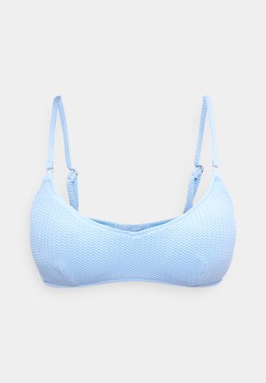 Φωτεινό γαλάζιο σουτιέν με ανάγλυφη υφή, ρυθμιζόμενους λεπτούς ιμάντες και διακριτικό σχέδιο ζιγκ-ζαγκ, σε απλό φόντο.