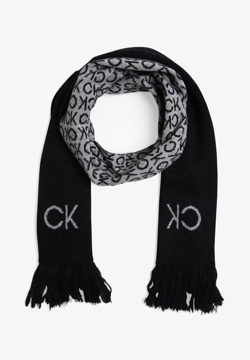 Écharpe tricotée noire et grise avec extrémités à franges, présentant des motifs répétitifs du logo CK sur le côté gris et de grandes lettres CK sur les extrémités noires.