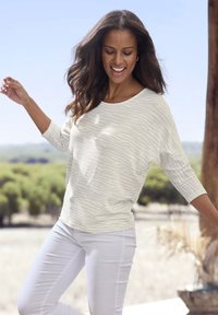 Light gray top with a subtle zebra pattern, wide neckline, and three-quarter sleeves, paired with white fitted pants.
