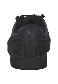 Zapatilla negra con un upper de cuero liso, cierres de cordones, lengüeta acolchada y una suela de goma texturizada. Presenta un logo gris en el talón.