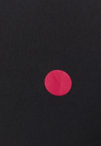 Black fabric with a textured pattern featuring a large pink circular detail. The circle is solid and bright against the dark background.