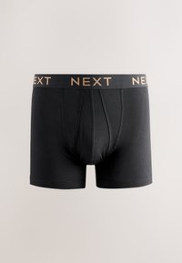 Boxer da uomo neri con logo beige "NEXT" sulla fascia, vista frontale con cuciture e pannelli visibili.