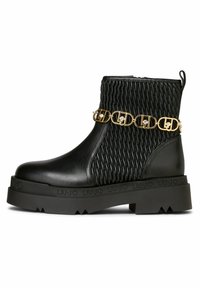 Schwarze Knöchelstiefel mit einer strukturierten Oberfläche und gewobenem Design, goldfarbener Hardware-Kettenakzent und einer robusten Gummisohle mit Logodetail.