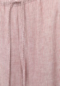 Red and white striped fabric featuring a soft texture with a drawstring waistband and pleats. Design highlights a subtle pattern throughout.