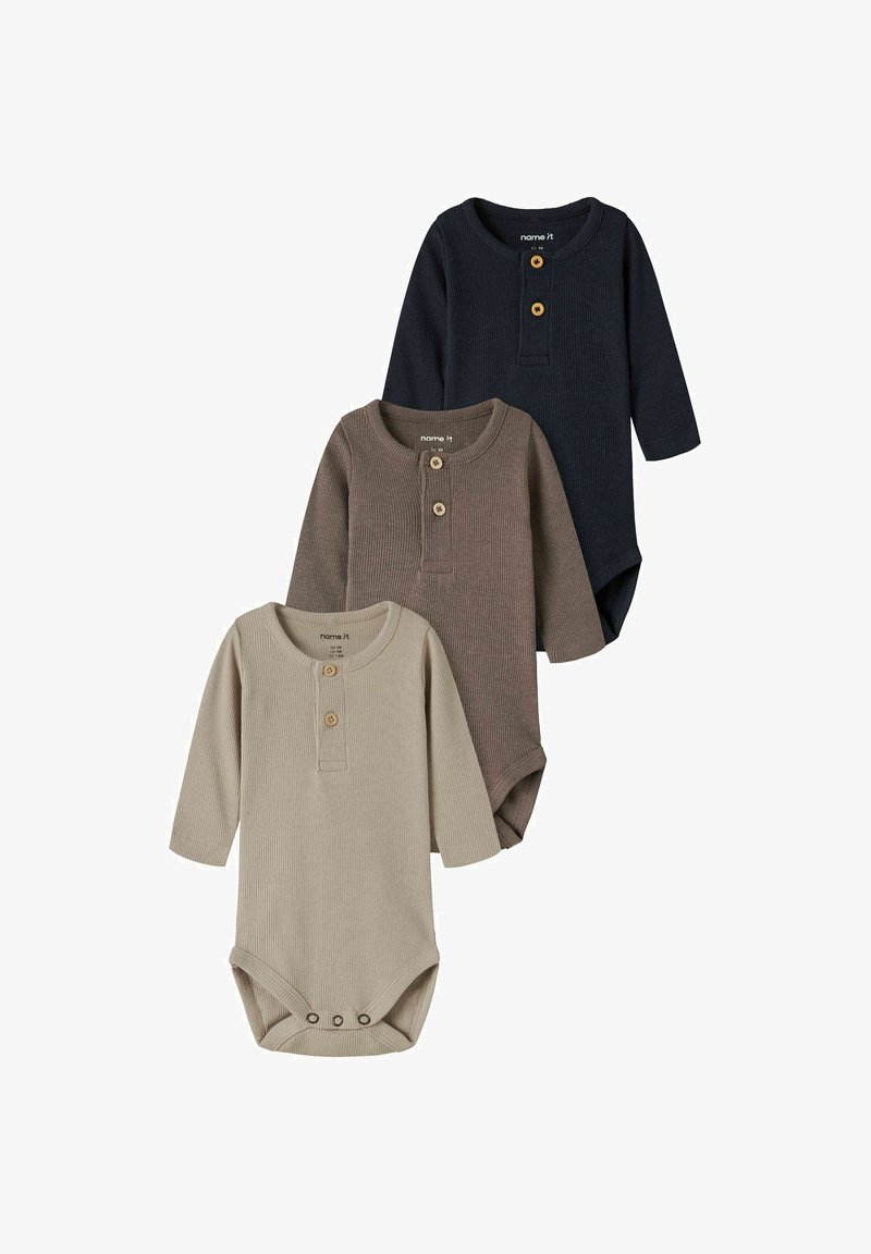 Trois bodies bébé à manches longues côtelés en beige, marron et bleu marine avec des boutons sur la poitrine et des fermetures pression en bas.
