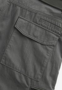 Dark gray cargo pants featuring a large patch pocket, thick stitching, and a smooth, textured fabric. No visible hardware or patterns.
