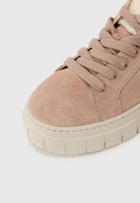 Sneaker in suede rosa con punta arrotondata, parte superiore testurizzata e suola in gomma crema con un accento cucito. I lacci sono piatti e intrecciati.